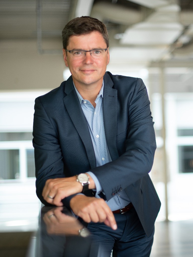 Dipl.-Ing. Karsten von Rabenau, Geschäftsführer der TÜV SÜD Pluspunkt GmbH, im blauen Anzug und hellblauen Hemd, mit Brille, professionelles Business-Porträt